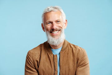 Handsome smiling bearded mature man with stylish gray hair wearing brown leather jacket looking at...