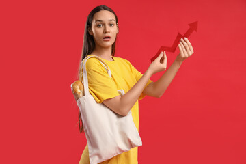 Young woman with bag of food and arrow on red background. Price rise concept