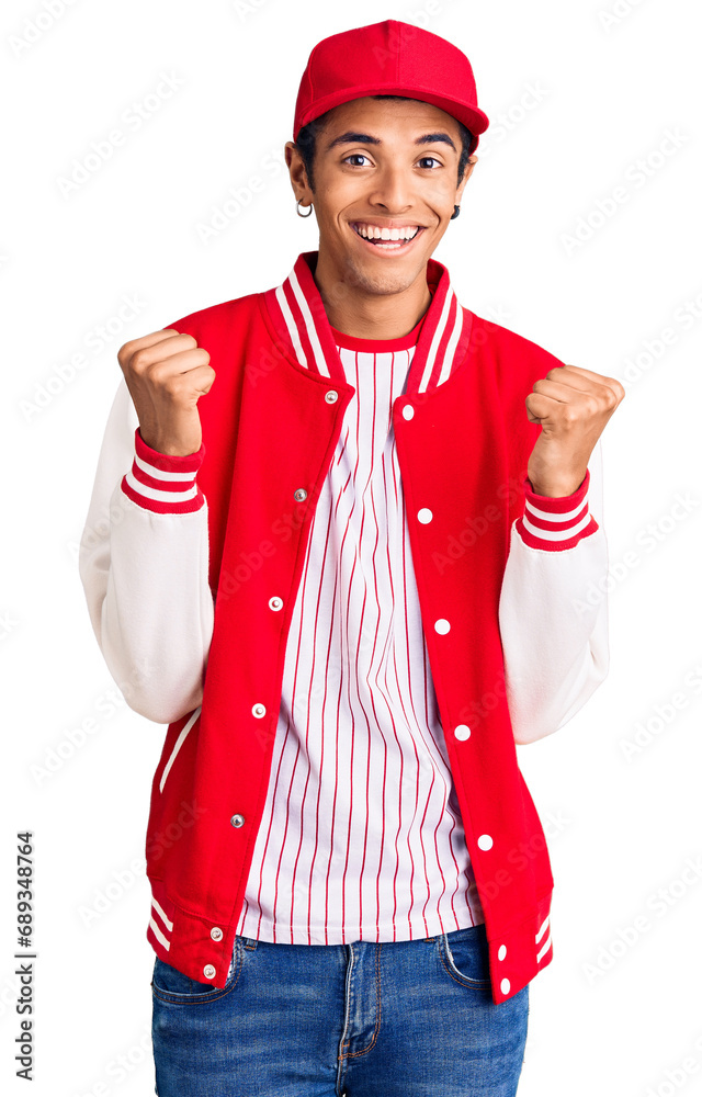 Wall mural Young african amercian man wearing baseball uniform celebrating surprised and amazed for success with arms raised and open eyes. winner concept.