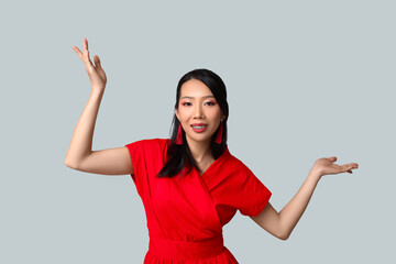 Beautiful young happy Asian woman on grey background. Chinese New Year celebration