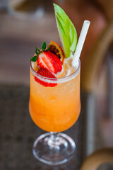 Cocktail of orange juice in glass with strawberries and apple, selective focus