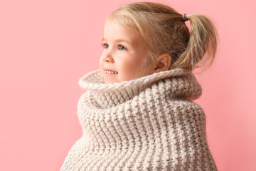 Cute little girl in knitted scarf on pink background