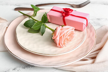 Beautiful table setting with rose and gift for Valentine's Day on white grunge background