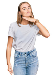 Beautiful young blonde woman wearing casual white t shirt cutting throat with hand as knife, threaten aggression with furious violence