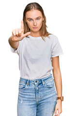 Beautiful young blonde woman wearing casual white t shirt pointing with finger up and angry expression, showing no gesture