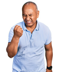 Hispanic middle age man wearing casual t shirt angry and mad raising fist frustrated and furious while shouting with anger. rage and aggressive concept.
