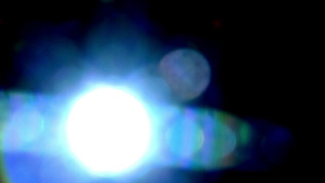 Slowly circling spectrum star shaped light leaks and lens flare on black.