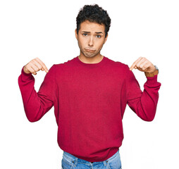 Young handsome man wearing casual clothes pointing down looking sad and upset, indicating direction...