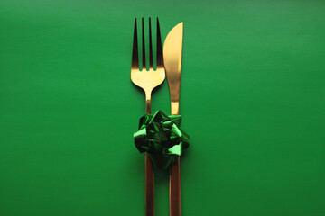cutlery in gold color with a green bow on a green background
