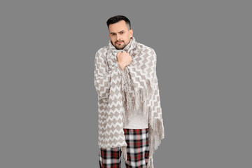 Sick young man with plaid on grey background