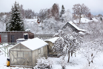 A personal plot with sheds, a greenhouse and fruit trees covered with snow