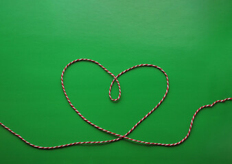 heart made of red and white thread on a green background