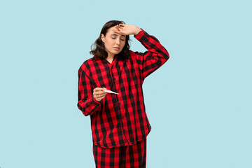 Fototapeta premium Sick young woman with thermometer on blue background