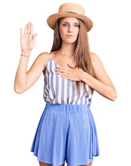 Obraz na płótnie Canvas Young beautiful blonde woman wearing summer hat swearing with hand on chest and open palm, making a loyalty promise oath