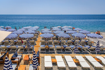 Pebble beach along Promenade des Anglais with beach umbrellas and chairs with the turquoise water...
