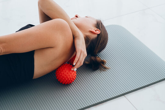 Woman lying on small balls to eliminate back pain, massage stiff muscles and thoracic back pain, perform exercises to relieve pain in spine. Relaxation and stretching of muscles