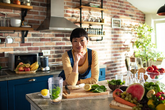 Portrait of young woman nutritionist in kitchen with fresh vegetables on countertop