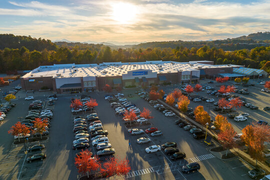 Top view of american Walmart grocery store parking lot with parked cars at sunset in autumnal season. US food retail. Asheville, USA - October 23, 2022.