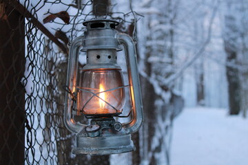 kerosene lantern shines on a mesh fence in winter