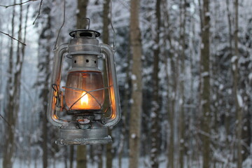 kerosene lantern shines near a fantasy scary tree in winter