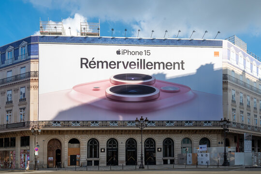 Paris, France - 6 d&eacute;cembre 2023: Affiche publicitaire g&eacute;ante Apple iPhone 15 couvrant les &eacute;chafaudages des travaux de restauration sur la fa&ccedil;ade d'un immeuble parisien abritant un Apple store