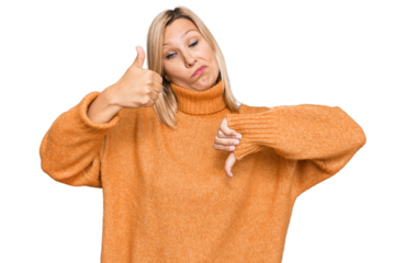 Middle age caucasian woman wearing casual winter sweater doing thumbs up and down, disagreement and agreement expression. crazy conflict