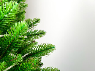 Close-up of branches of an artificial green Christmas tree with a garland of yellow Christmas lights. Family celebration. New Year background