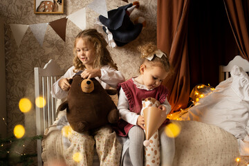 sisters girls playing in children's room, on bed at home with toy animal