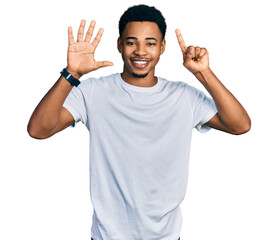 Fototapeta premium Young african american man wearing casual white t shirt showing and pointing up with fingers number six while smiling confident and happy.