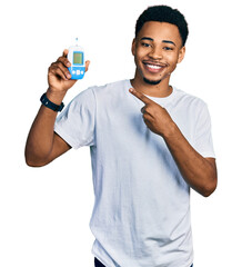 Young african american man holding glucometer device smiling happy pointing with hand and finger