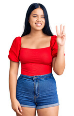 Obraz premium Young beautiful asian girl wearing casual clothes showing and pointing up with fingers number three while smiling confident and happy.