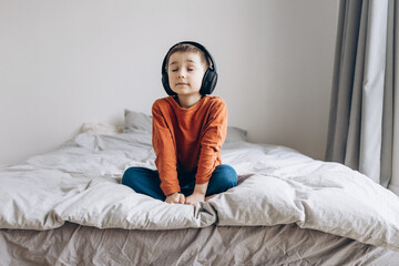 Fototapeta premium Happy smiling child enjoys listen to the music in headphones at home