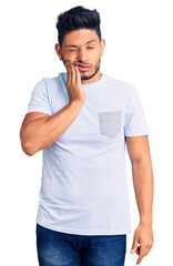 Fototapeta na wymiar Handsome latin american young man wearing casual clothes touching mouth with hand with painful expression because of toothache or dental illness on teeth. dentist