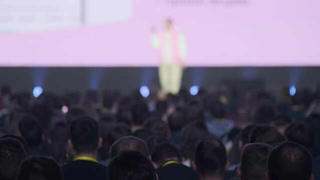 Handheld shot of large crowd of businesspeople attending global workshop in conference hall