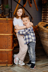 Little brother and sister hugging in the interior of a country house.