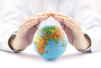 Planet Earth globe protected by hands.