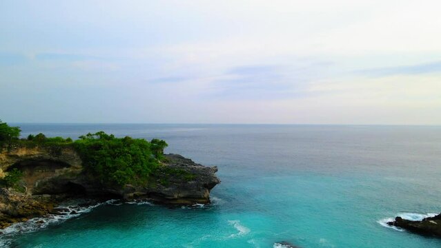 Aerial Forward Shot Of Tranquil Blue Sea By Rocks Under Sky - Bali, Indonesia