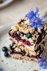 Baked oatmeal squares with fresh blueberry on beige background with cornflowers close up. Menu, recipe