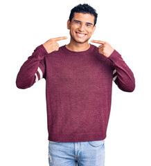 Hispanic handsome young man wearing casual clothes smiling cheerful showing and pointing with fingers teeth and mouth. dental health concept.