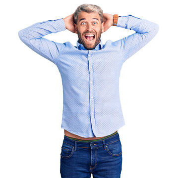 Young handsome blond man wearing elegant shirt crazy and scared with hands on head, afraid and surprised of shock with open mouth