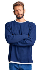 Handsome blond man with beard wearing casual sweater skeptic and nervous, disapproving expression on face with crossed arms. negative person.