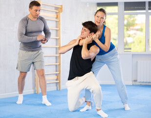 Young man and woman in sparring improve skill of performing strangulation and neutralizing enemy. Training in martial art of krav maga