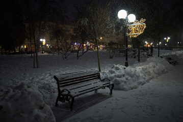 snowy bench in the park at the winter night