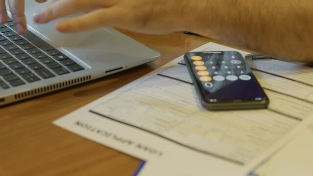 Loan application on the desc in front of the man working on the laptop. . High quality 4k footage