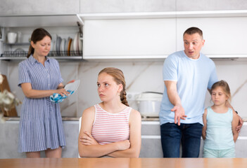 Fototapeta premium Parents scolding teenager daughter in home kitchen