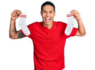 Young hispanic man holding socks smiling and laughing hard out loud because funny crazy joke.