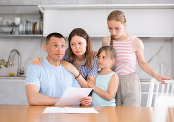 Thoughtful man reads expense estimate document and is saddened by bad news about financial...