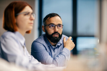 Portrait of a businessman discussing at office while his coworker is sitting in a blurry foreground.
