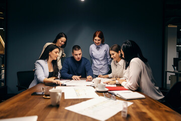 Engineers having briefing in a boardroom and discussing blueprints.