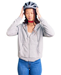 Young beautiful chinese girl wearing bike helmet suffering from headache desperate and stressed because pain and migraine. hands on head.
